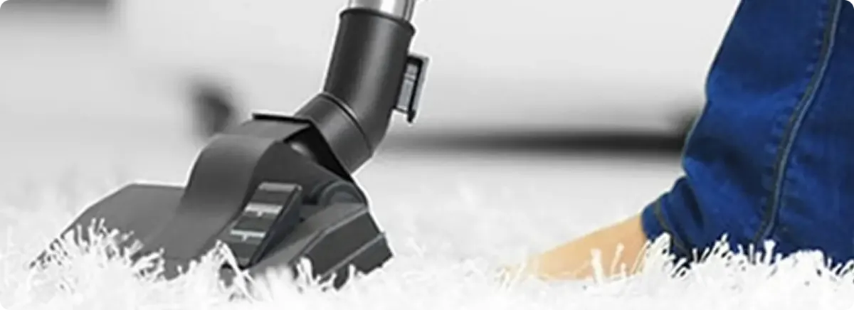 Close-up of a professional vacuuming a white carpet in Layton.